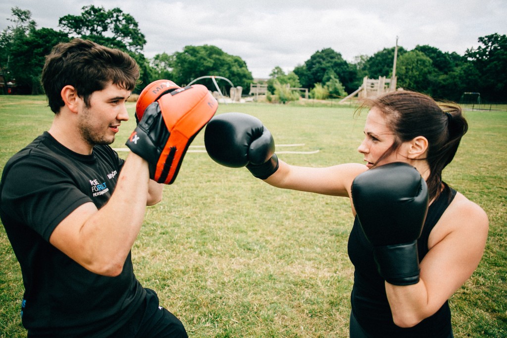 Personal trainer in Essex holding pads for a client during an outdoor boxing fitness session.