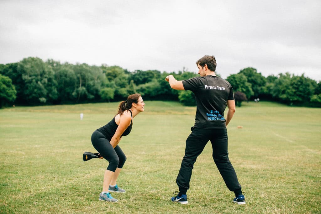 Personal Training client doing kettlebell swings outdoors in Essex park