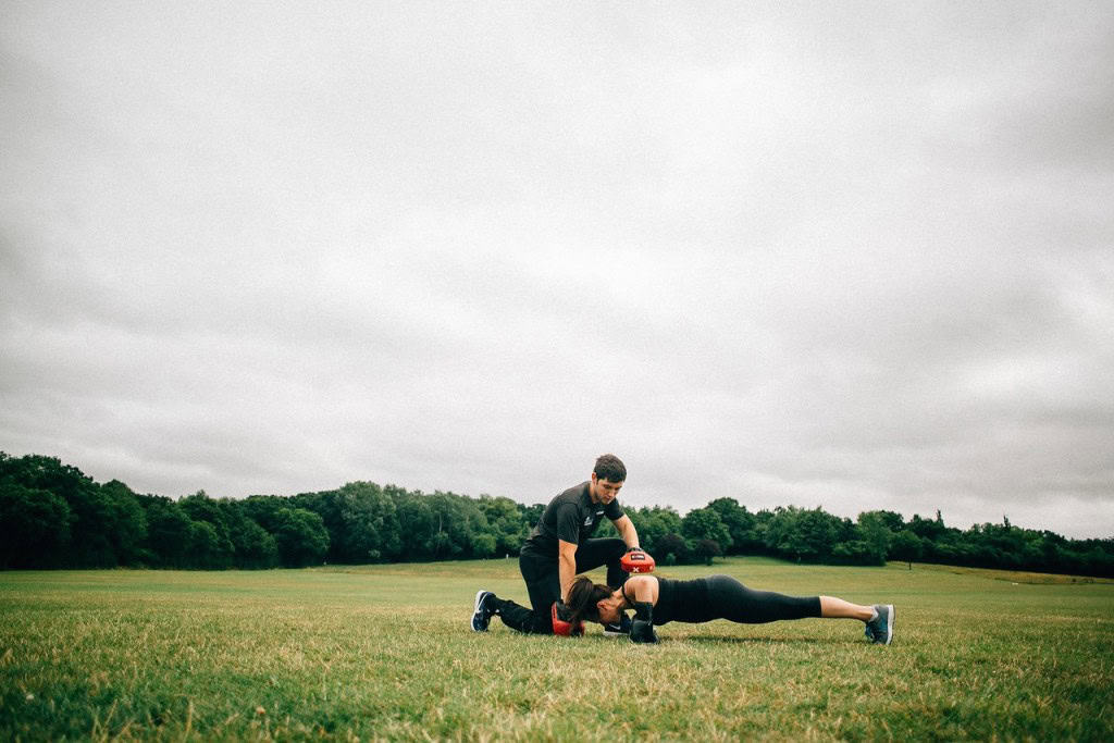 Personal trainer in Essex coaching a client during an outdoor press-up workout in the park.
